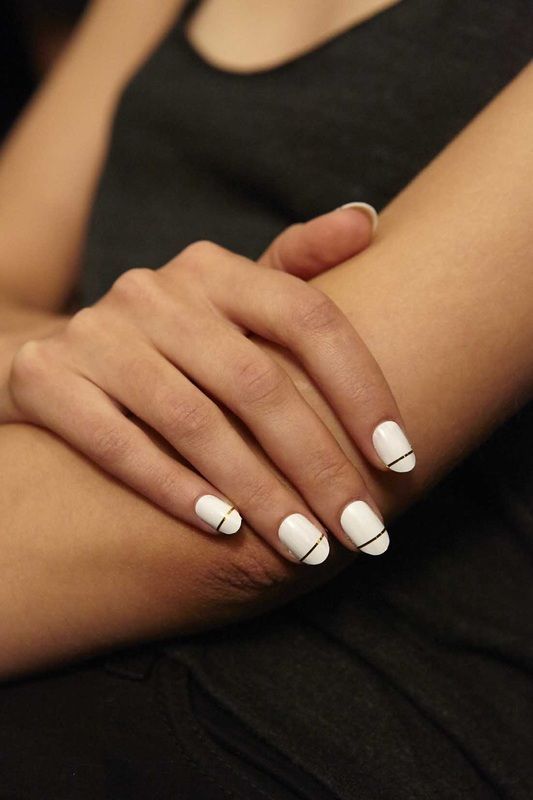 a modern take on French nails done in white and with a gold stripe