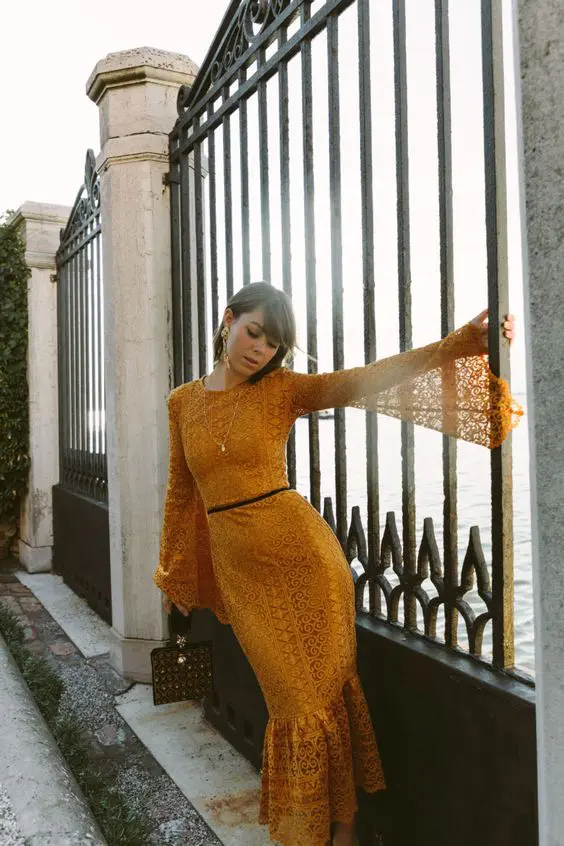 a mustard lace mermaid midi dress with bell sleeves and a small bag for a party or a date