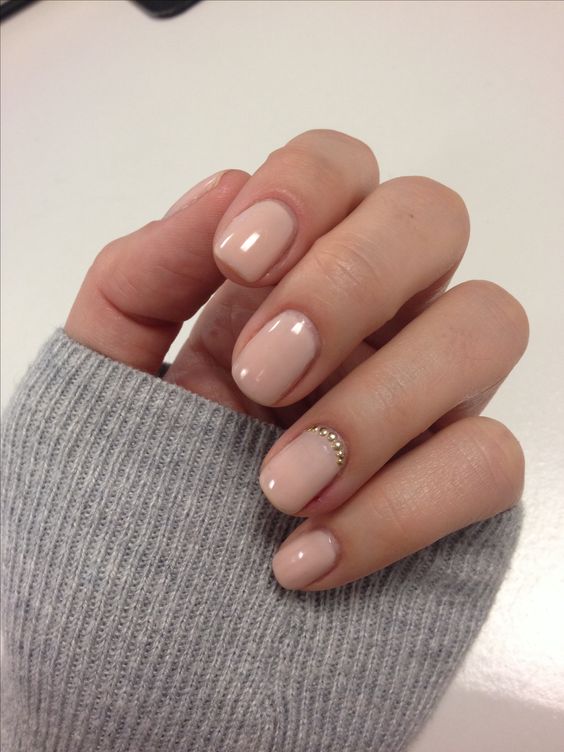 nude nails spruced up with a statement nail with gold beads at the cuticle