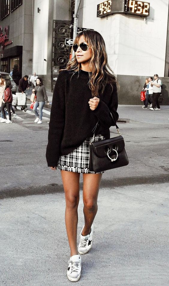 a casual look with a black sweater, a tweed mini skirt, white sneakers and a black bag