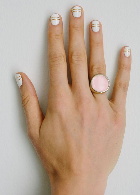 white nails with gold stripes are a cool and bold minimalist idea