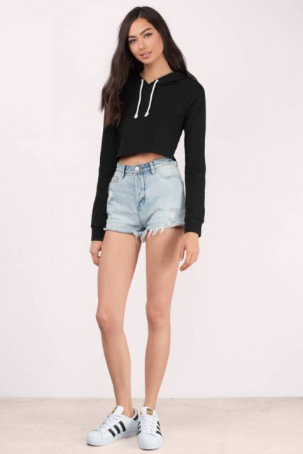 With denim shorts and white and black sneakers