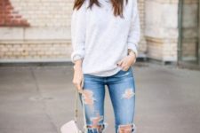 With distressed jeans, brown shoes and beige bag