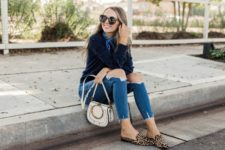 With distressed jeans, white small bag and navy blue sweater