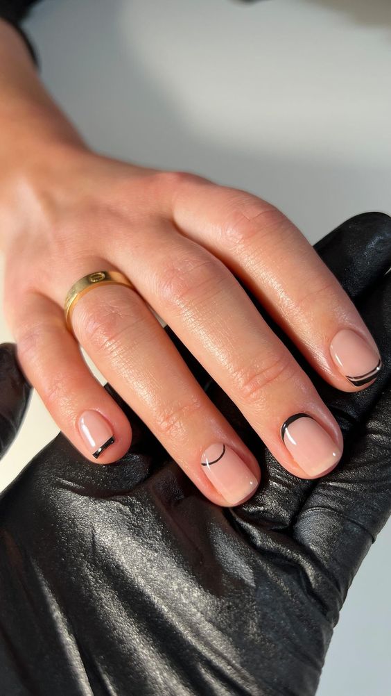 a blush and black French manicure with tips placed on different parts of the nails is a cool idea