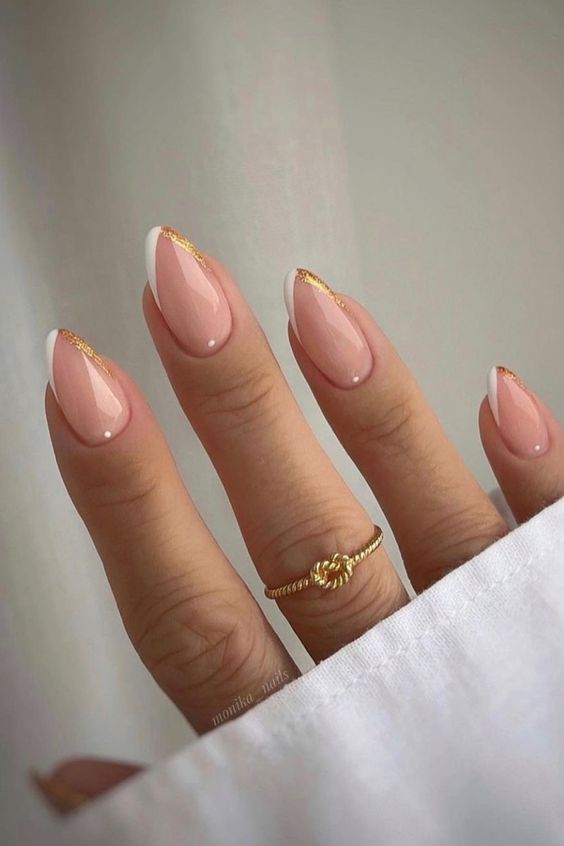 a glam French manicure done in blush, white and gold glitter accenting the almond shape of the nails