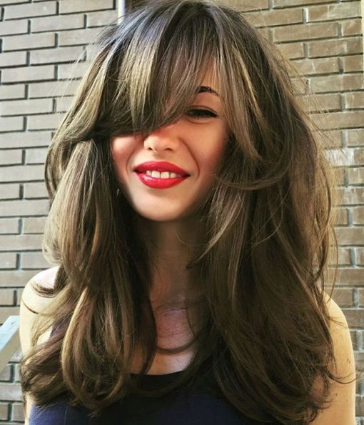 a long layered haircut with cheek-skimming bangs looks flirty and sexy