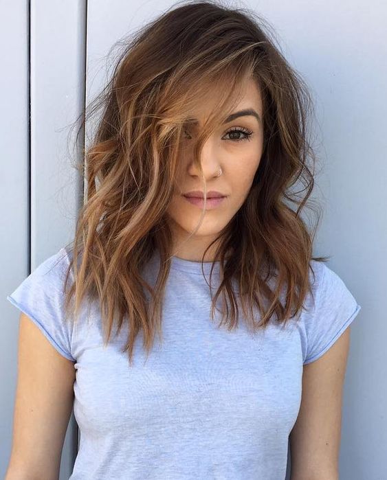 a stylish medium haircut with layers, bangs and blonde balayage for a chic look