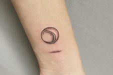 Black-contour tennis ball tattoo on the wrist