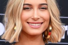 Hailey Bieber wearing a gold blonde long bob with waves, central parting and a lot of texture looks really posh