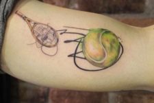 Tennis ball and racket tattoo on the arm