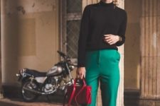 With black turtleneck, cap, emerald trousers and red bag