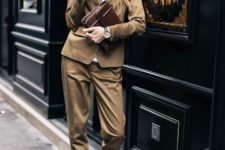 With brown blazer and trousers, hat and leather clutch