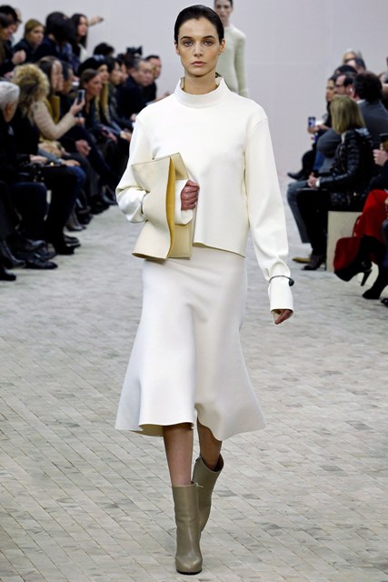With white loose sweatshirt, beige clutch and gray boots