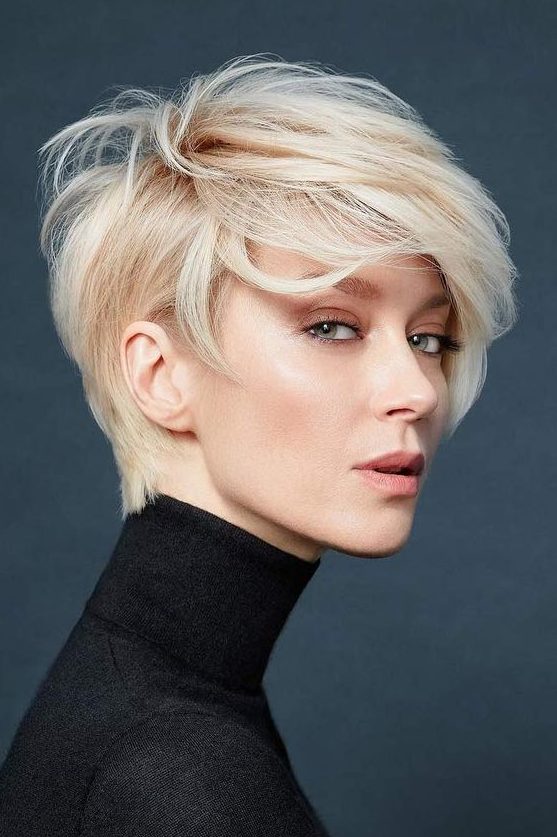 a beautiful and voluminous warm blonde long pixie cut with straight hair looks very bold and very stylish