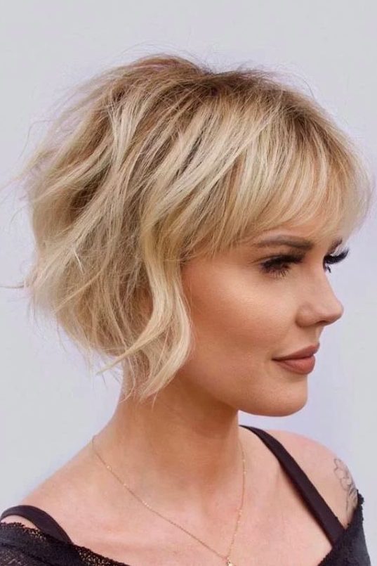 A lovely ear length blonde bob with a classic fringe and messy waves plus a lot of volume is very chic