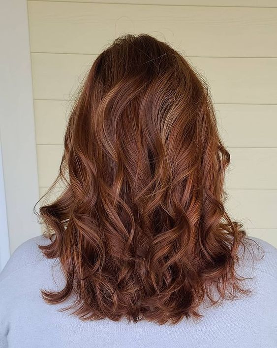 Chic medium length auburn hair with gold blonde highlights and waves down, with a lot of volume is wow