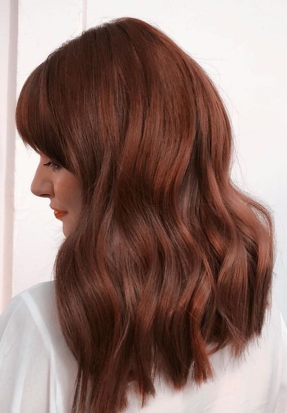 elegant medium-length auburn hair, with bangs, waves and a lot of volume is a stunning idea for a bold look in the fall