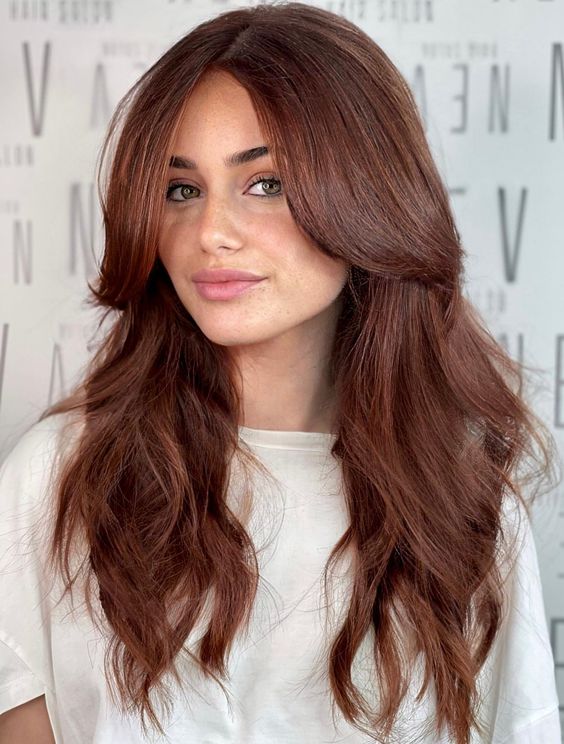 impressive long auburn hair with a lot of volume and waves, with long curtain bangs, is a super chic and catchy idea