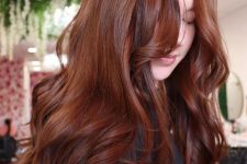 long auburn hair with some highlights, with waves and volume, with bangs is a stylish and eye-catchy solution for the fall