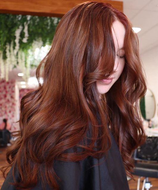 long auburn hair with some highlights, with waves and volume, with bangs is a stylish and eye-catchy solution for the fall