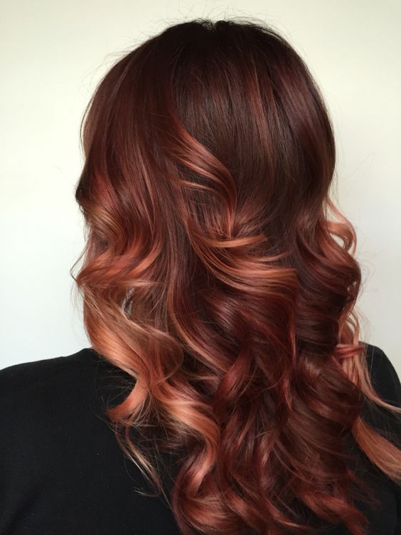 long dark auburn hair with copper and red highlights, with waves and volume, is a bold solution to make a statement