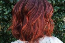 medium-length auburn hair with a darker root and an ombre touch, with waves and volume, is a catchy and chic idea