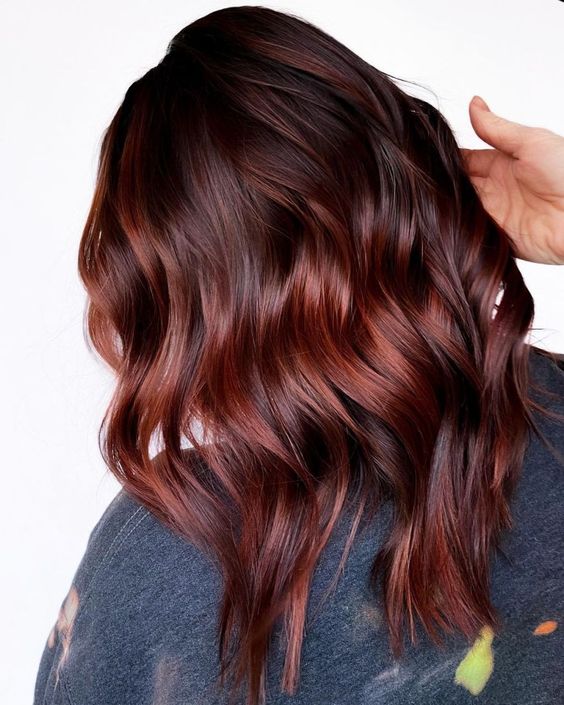 Medium length auburn hair with brighter red highlights, waves and a bit of volume is a catchy and bold idea