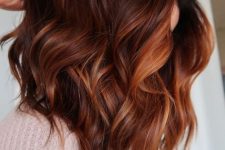 medium-length auburn hair with orange and copper highlights, with waves and volume, is a stunning solution that wows