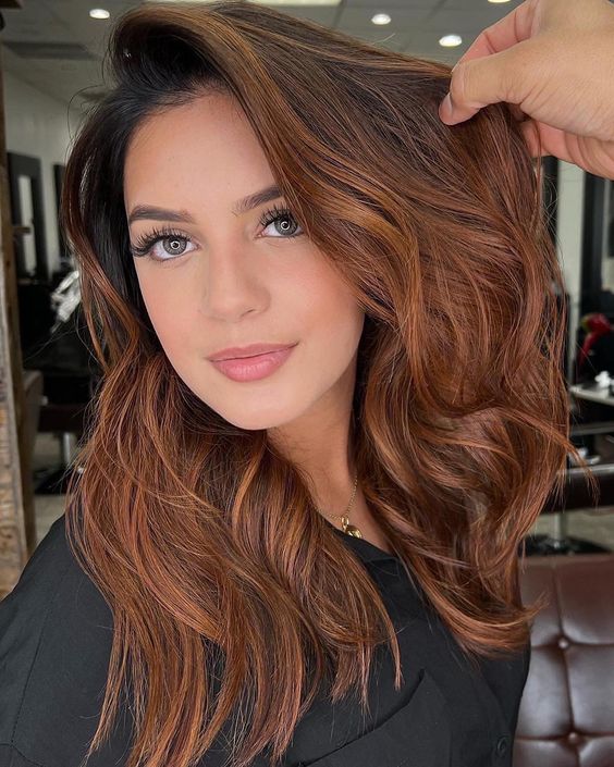 pretty medium-length auburn hair with a lot of volume and waves is a stylish and catchy idea for the fall