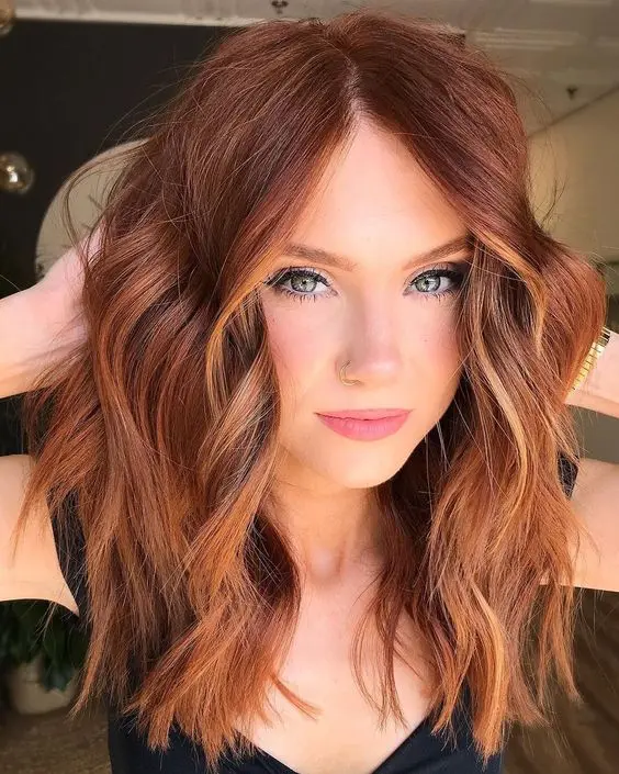 shoulder-length auburn hair with copper highlights and contouring, with messy waves and volume is a stylish and bold idea
