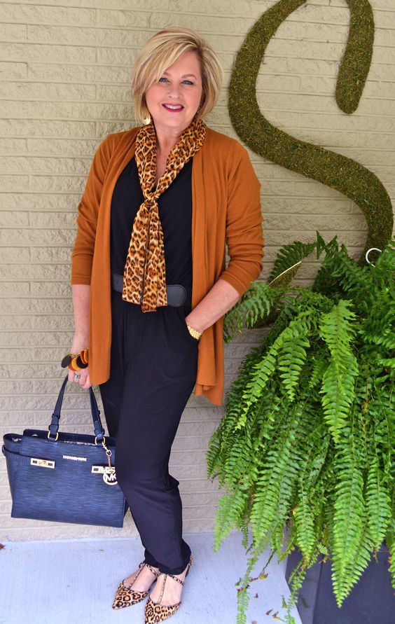 a navy jumpsuit, a rust cardigan, leopard flats and a scarf, a blue bag and statement earrings