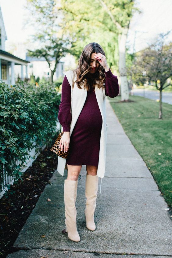 A plum colored sweater dress with a creamy long waistcoat, creamy tall boots and a leopard bag