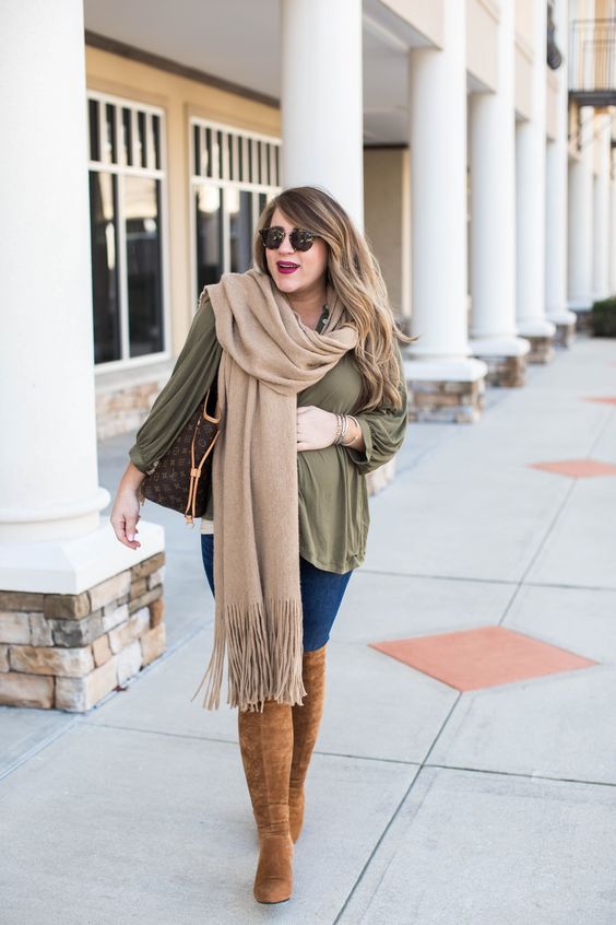 an olive green blouse, blue skinnies, tall rust boots, a beige scarf and a large bag