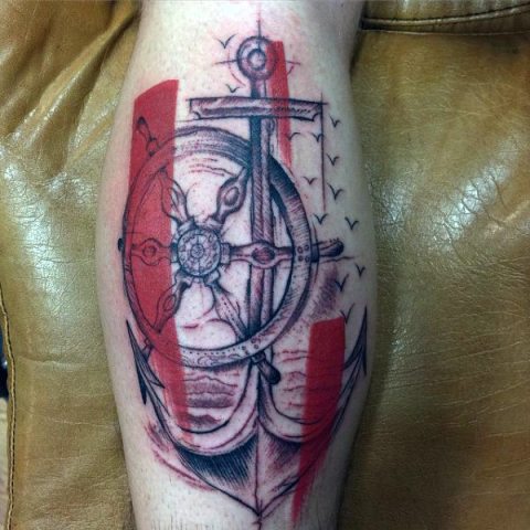 Abstract ship wheel and anchor tattoo on the leg