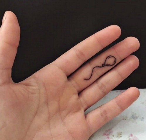 Black-contour balloon tattoo on the finger