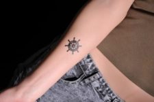 Small black ship wheel tattoo idea on the forearm