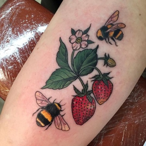 Strawberries and bees tattoo on the arm