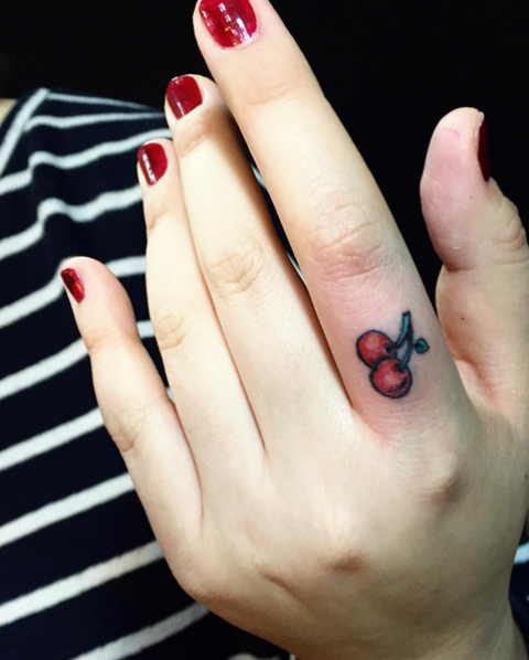 small cherry tattoo on woman's finger