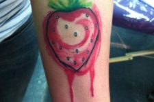 Watercolor strawberry tattoo on the forearm