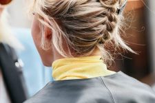 a backward braided updo with a tiny bun on top and some face-framing hair for a cool look