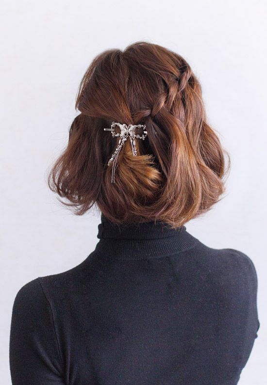 a beautiful half updo with a braid on one side and twist on the other, with waves down and a shiny hair piece