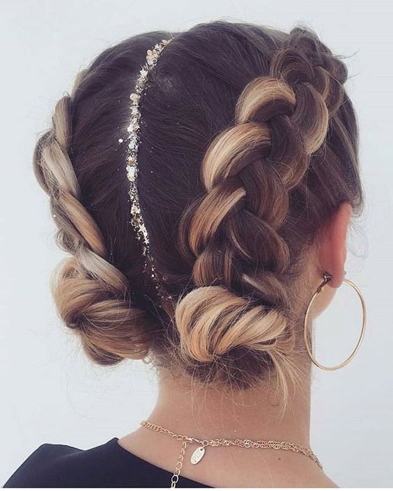 a holiday hairstyle of two large braids on the sides of the head ending up in buns, with glitter parting is wow