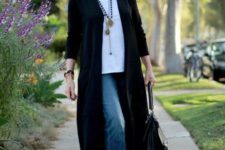 blue jeans, booties, a white top, a long black cardigan and layered necklaces plus a bag