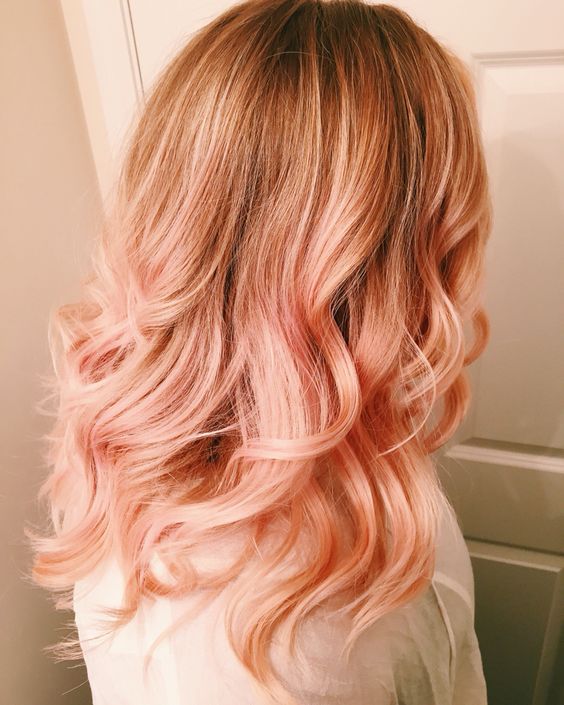 Long wavy hair in strawberry blonde, with some waves and a darker root is a cool and eye catchy idea to rock