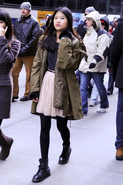 a black tee, a blush skirt, black tights and combat boots, an olive parka for a girlish feel