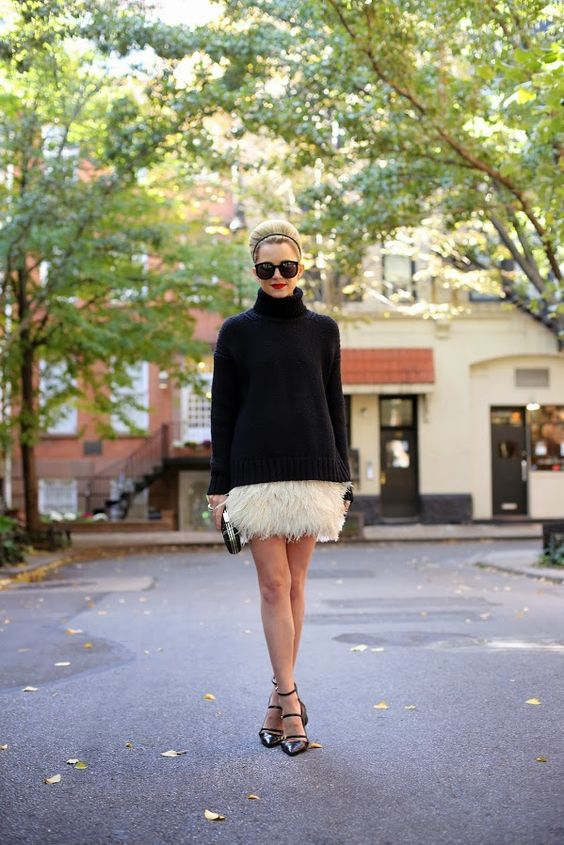 a black turtleneck oversized sweater, a white feather mini, black shoes and a black clutch