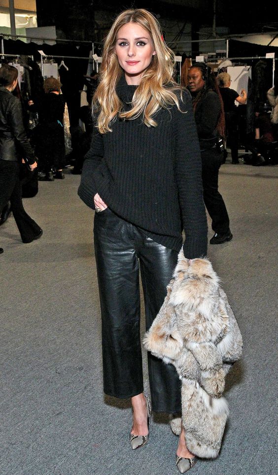 Olivia Palermo wearing cropped black leather pants, a black sweater, a faux fur waistcoat and snake print shoes