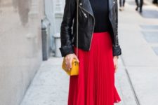 With black shirt, black leather jacket, yellow bag, pleated skirt and black ankle boots
