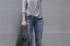 With gray shirt, distressed jeans, hat and high heels